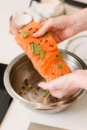 Female hands hold red fish fillet with spices. Cooking lightly salted red fish.の写真素材