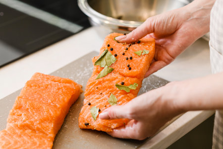 Female hands hold red fish fillet with spices. Cooking lightly salted red fish.の写真素材
