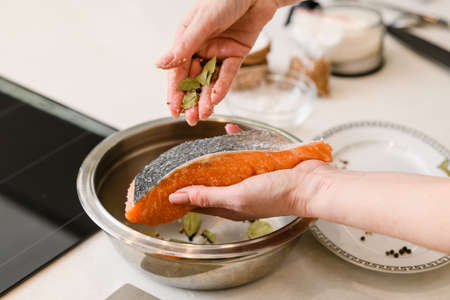 Female hands rubbing with spices fresh salmon fillet on cutting board.の写真素材