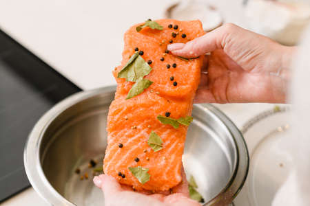 Female hands hold red fish fillet with spices. Cooking lightly salted red fish.の写真素材