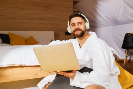 Young handsome bearded man with headphones and laptopの写真素材