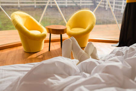 Male and female lying in bed with legs sticking from under the blanket.の写真素材