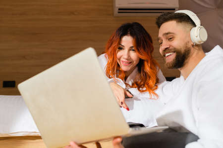 Young couple in bathrobes with a laptop. Man and woman watching a movie.の写真素材
