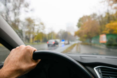 First-person view of the driver of the car. Man's hand on the steering wheel. Police car in the background. high quality photoの写真素材