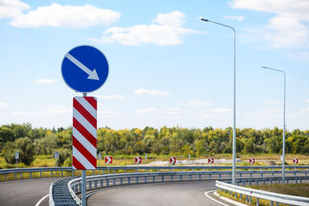 Separation barrier and direction sign detour on the right. Warning traffic sign.の写真素材