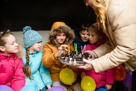 Dnipro, Ukraine - March 21, 2022: Children's birthday party in a bomb shelter during an air raid. Children taste birthday cake.のeditorial素材