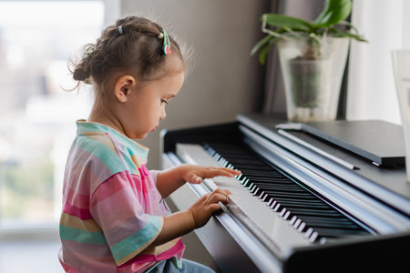 Cute little girl playing piano at a music school. Preschool child learning to play music instrument. Education, skills concept.の写真素材