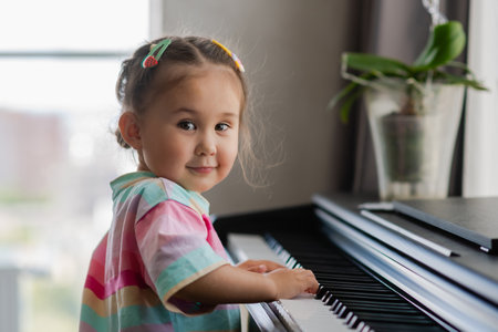 Portrait of beautiful little asian girl plays the piano. Preschool child learning to play music instrument. Education, skills concept. Little princess is happy playing the piano. happy childhoodの写真素材