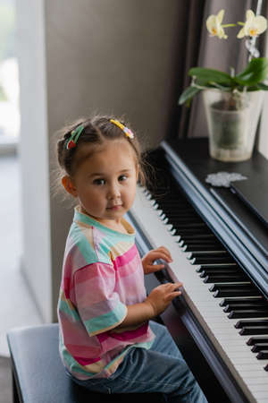 Cute little girl playing piano at a music school. Preschool child learning to play music instrument. Education, skills concept.の写真素材