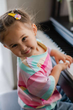 Portrait of beautiful little asian girl plays the piano. Preschool child learning to play music instrument. Education, skills concept.の写真素材