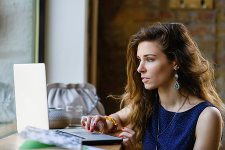Young attractive dreamy woman with laptop in coffee shop.の写真素材