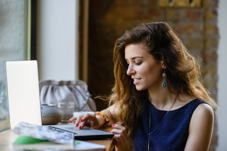 Young attractive dreamy woman with laptop in coffee shop.の写真素材