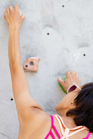 Sportswoman climber moving up on steep rock, climbing on artificial wall. Extreme sports and bouldering conceptの写真素材