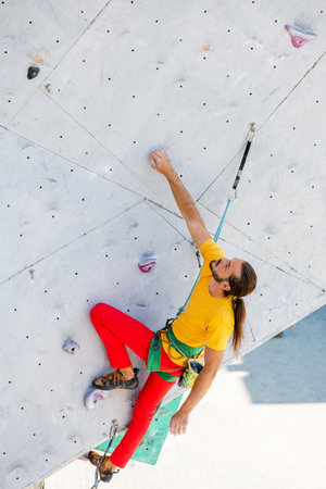 Young and fit man exercise free mountain climbing on outdoor practice wall. top view.の写真素材