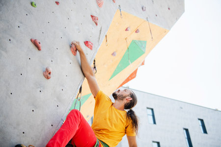 Young and fit man exercise free mountain climbing on outdoor practice wall.の写真素材
