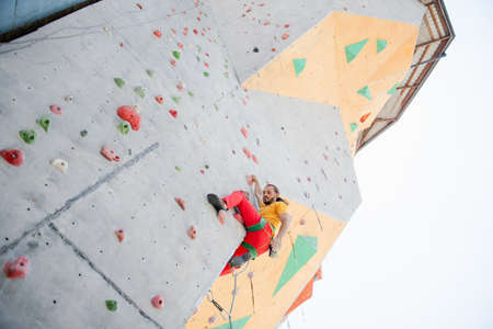 A man climbs up an artificial wall at a climbing wall. bottom view.の写真素材