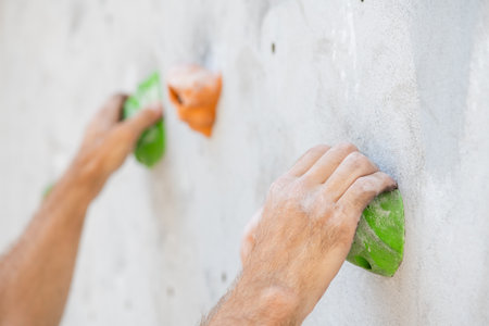 Close-up of a male hand smeared with magnesium powder grabbing a hold of a climbing wall.の写真素材