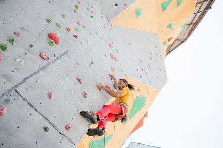 A man climbs up an artificial wall at a climbing wall. bottom view.の写真素材