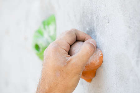Close-up of a male hand smeared with magnesium powder grabbing a hold of a climbing wall.の写真素材