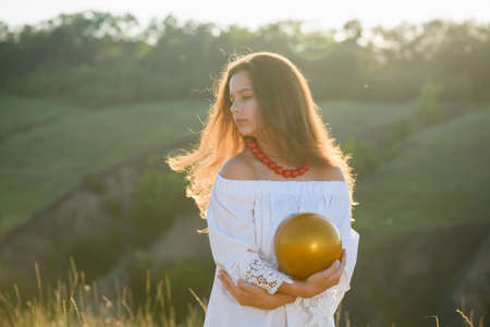 Teenage girl with a gymnastic ball on the background of a ravine. Sunset backlight.の写真素材