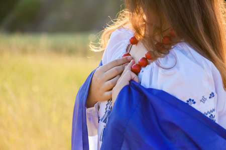 Hands of teenage girl with a Ukrainian flag on her shoulders. close-up. Girl dressed in national Ukrainian clothes.の写真素材