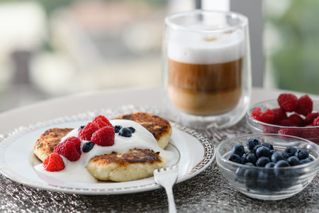 Cottage cheese pancakes for breakfast with blueberries and raspberries and sour cream.の写真素材