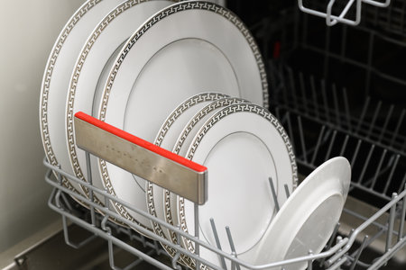 Open dishwasher with clean dishes in a white kitchen. Clean plates, cups and dishes. Nobody. selective focus.の写真素材