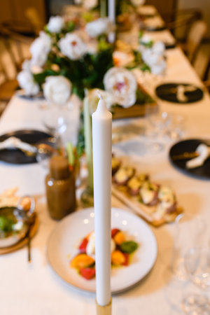Beautiful restaurant table setting background with candle, cutlery, plates and appetizer food for eventの写真素材