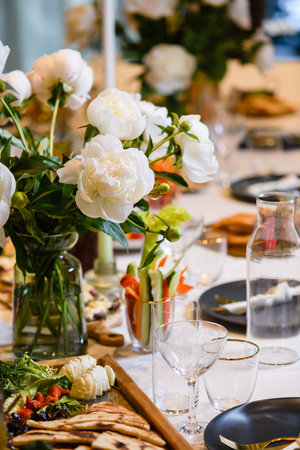 Beautiful table event restaurant wedding celebration setting with peonies flowers, plates, food, cutlery and glassesの写真素材