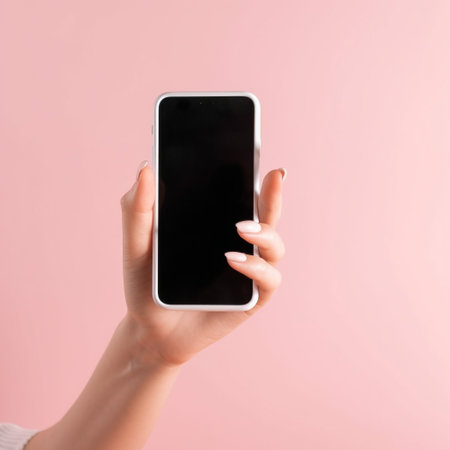 Cropped image of woman holding smartphone with blank screen isolated on pinkの素材