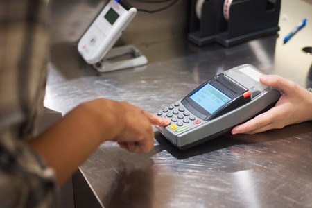 Woman hand push pin code on credit card terminal for buying things