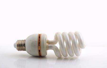 Used energy-saving lamp on a white table isolate