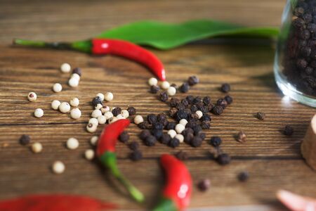 Red chilly peppers with black and white peppers background