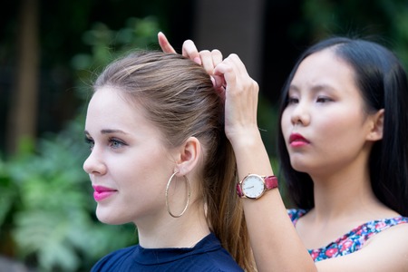 Two young beauty girlfriend makes hairstyle outdoorの写真素材