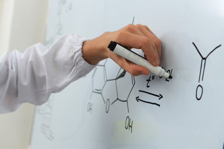 The researcher writes a chemical formula on a white boardの写真素材