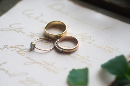 Wedding ring and invitation on tableの写真素材