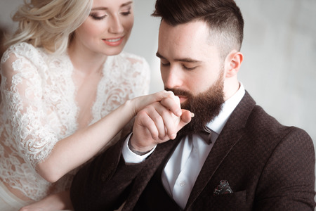 Young bearded guy the groom kisses the beautiful bride's handの写真素材