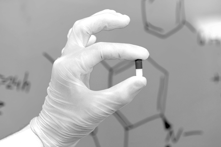 Hand a scientific medical researcher holding a tablet, on a blackboard writing chemical formulasの写真素材