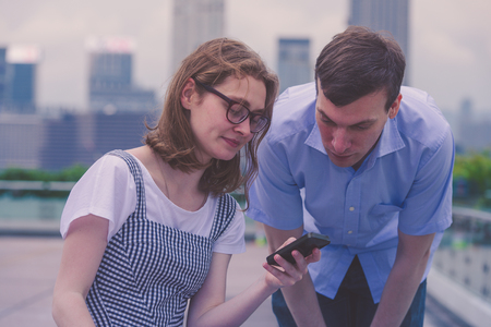 A guy and a girl are looking together in a mobile phone