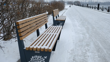Bench in the snow-covered city parkの写真素材