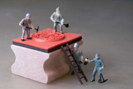 Miniature workers repaire rubber stampの写真素材