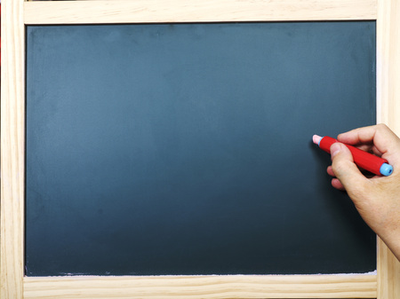 Hand with chalk at the empty blackboardの写真素材