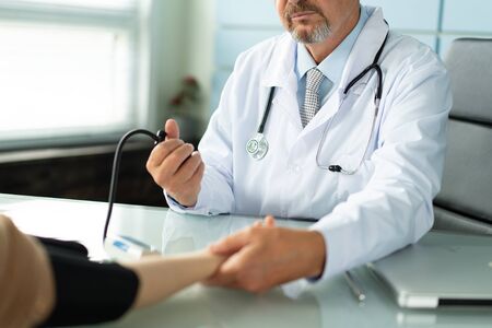 A doctor measures the blood pressure of a patient closeup photo