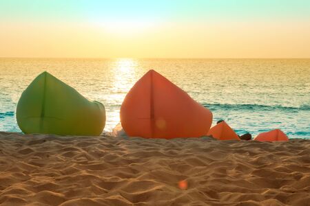Inflatable chairs on the beach on evening sunsetの写真素材