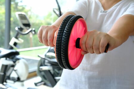 woman in gym with gymnastic wheel roller does exercises for bellyの写真素材