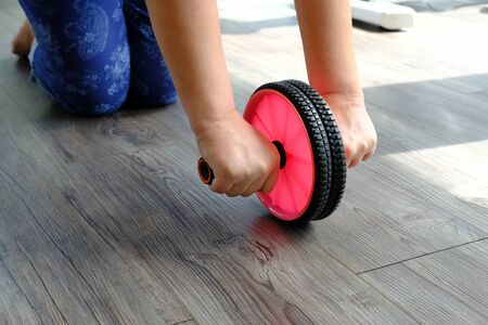 woman in gym with gymnastic wheel roller does exercises for bellyの写真素材