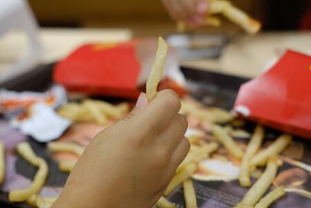 Hand holding fried potatoes in a fast food cafe closeup photoの写真素材