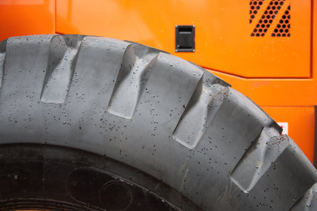 A CloseUp Image Featuring a Heavy Machinery Tire Against a Bright Orange Backgroundの写真素材