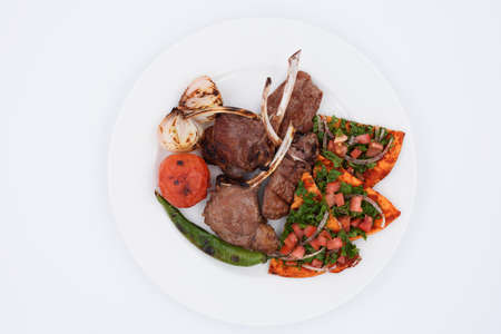 Lamb chops grilled with vegetables on a white plateの写真素材