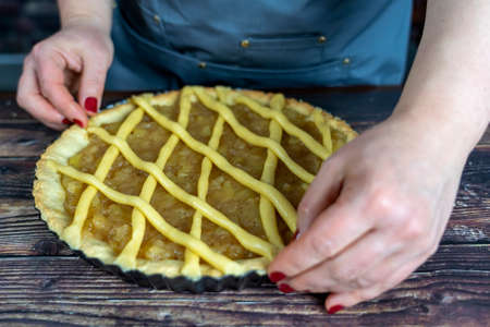 Women preparing delicious apple tart or pie large  on wood table background.の写真素材
